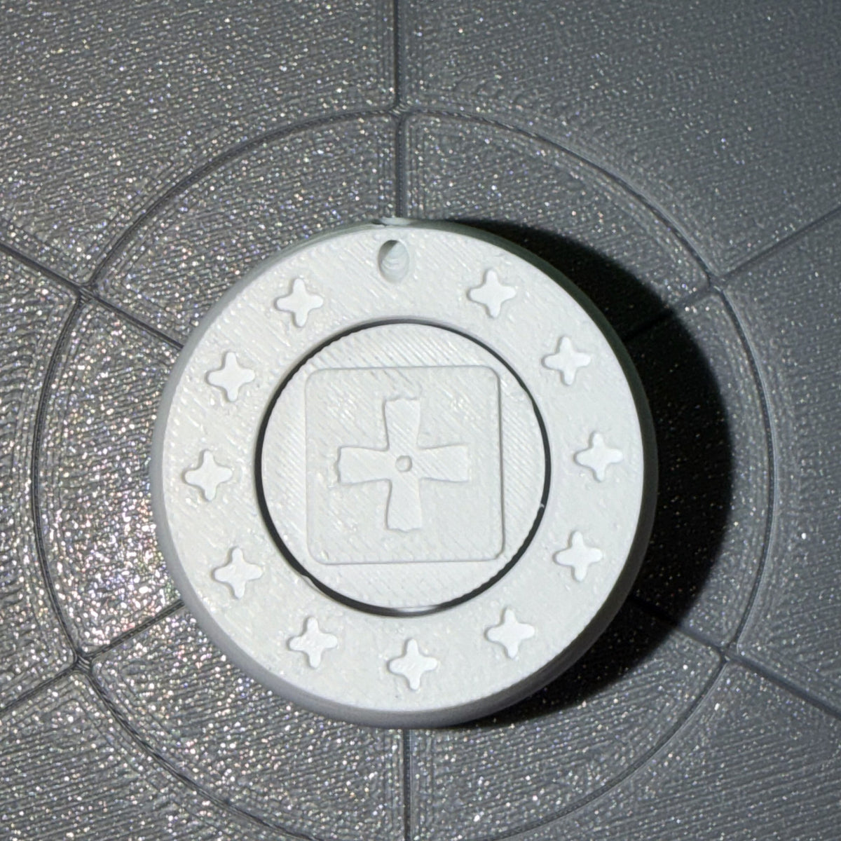 The Orban Clicker keychain seen from directly above, showing the Coptic cross on the cap and the eleven crosses around the rim